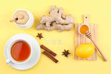 Ginger roots, cup of tea, cinnamon and anise on yellow background