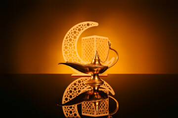 Wall Mural - Aladdin lamp of wishes and decorative crescent for Ramadan on table against dark yellow background