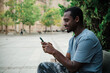 © alvaro - Man using a mobile phone sitting on a bench outdoors.