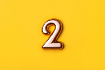 Metal number two on a yellow background. Top view.