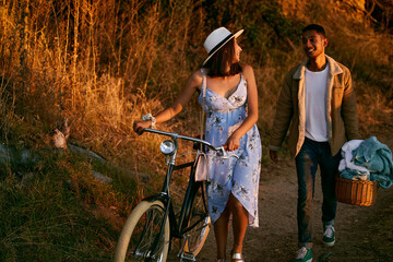 Poster - Romantic, happy and couple on a picnic in a park for a date, holiday and love in Indonesia. Travel, smile and man and woman walking in nature for romance, peace and relax with food during sunset