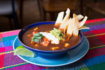 Wall Mural - Tortilla soup, also called Aztec soup, is a traditional Mexican soup. The soup is made with broth of ground tomatoes, garlic and onion, seasoned with epazote, and served with fried strips of corn.