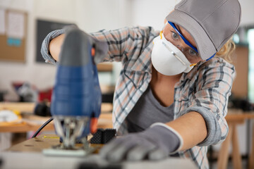 female carpenter cutting wood using a power saw