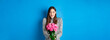 Leinwandbild Motiv Valentines day concept. Happy attractive woman receive surprise flowers, looking thankful at bouquet of pink roses, standing on blue background