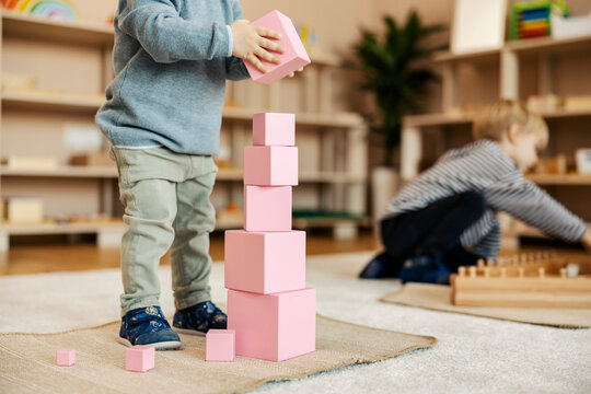 Cropped picture of a toddler building a tower with wooden blocks and playing games with montessori toys.