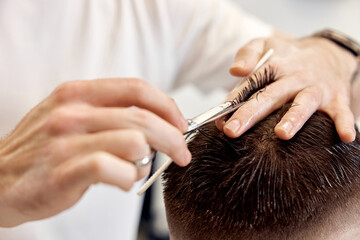 hairdresser does haircut for man using comb and grooming scissors