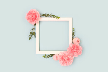 Wall Mural - square frame made of pink rose, carnation flowers and green eucalyptus branches on a blue background