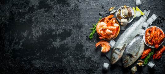 Wall Mural - Raw fish and seafood on a stone Board with ice cubes and lime slices.