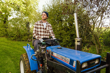 Man riding lawn mower while gardening in backyard