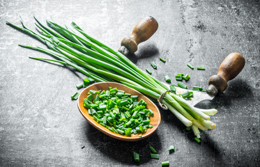 Wall Mural - Chopped green onion in a wooden plate with a knife.