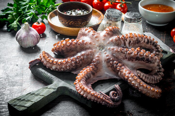 Canvas Print - Octopus on a cutting Board with spices and tomatoes.