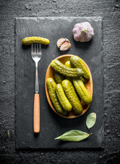 Poster - Preserved cucumbers the plate on a stone Board with the Bay leaf and garlic.