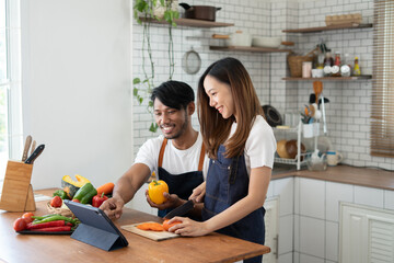 Wall Mural - Couple cooking together. Happy young couple cooking together in the kitchen. valentine day concept.