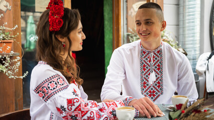 Wall Mural - Emotional portrait of a happy young couple in love, a family hugging, holding hands in the city of Lviv in traditional Ukrainian shirts, holding hands. Young people hug in the old town of Lviv