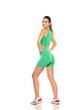© vladimirfloyd - young sporty smiling woman in green shorts and top posing on white studio background. Side, profile view