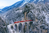 Fototapeta Krajobraz - Aerial view of Train passing through famous mountain in Filisur, Switzerland. Landwasser Viaduct world heritage with train express in Swiss Alps snow winter scenery.
