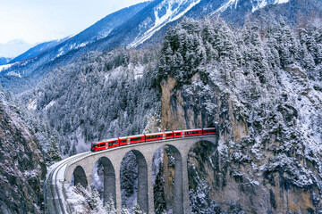 Wall Mural - Aerial view of Train passing through famous mountain in Filisur, Switzerland. Landwasser Viaduct world heritage with train express in Swiss Alps snow winter scenery.