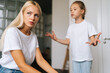 © dikushin - Close-up face of unhappy despair pensive young mother sitting on sofa listening mad little child daughter scolding, raising voice, screaming to at home. Concept of family problems, conflict, crisis.