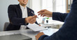 © Studio Romantic - Two young people make a business deal and sign a contract agreement. Smiling agent sitting at his office desk and handing over a pen and a paper document to his client. Cropped shot. Banner background