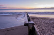 Groyne at beach leading down to sea with the sunrise