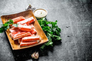 Sticker - Crab sticks on a wooden plate with greens and sauce.