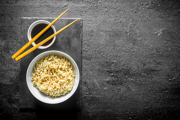 Sticker - Noodles in bowl on a stone Board with soy sauce and chopsticks.