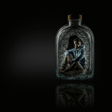A Drunk Alcoholic Addicted Man Trapped Inside A Liquor Bottle Isolated On Black Background With Reflection And Copy Space, Generative AI