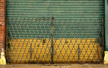 Security Gate On Old Green And Yellow Corrugated Metal Garage Door 