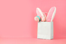 Easter Bunny Ears And Eggs In A Paper Bag On Pink Background With Copy Space
