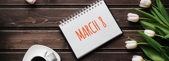 Wall Mural - White Tulip flowers with a Cup of coffee on a wooden table. Greeting card with lettering March 8. Top view, flat lay