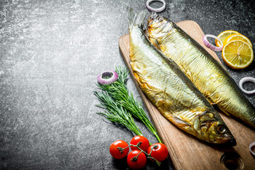 Wall Mural - Smoked fish on a wooden cutting Board with tomatoes, dill and lemon slices.