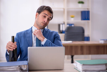 Poster - Young male employee drinking alcohol at workplace