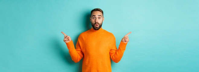 Shopping and advertisement concept. Excited man buyer pointing fingers sideways, showing two choices products, left and right banners, standing over light blue background