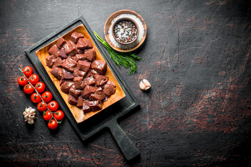 Poster - Pieces of raw liver on a cutting Board with tomatoes and spices.