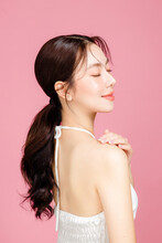 Young Asian Woman Gathered In Ponytail With Natural Makeup On Face Have Plump Lips And Clean Fresh Skin Wearing White Camisole On Isolated Pink Background. Portrait Of Cute Female Model In Studio.