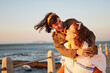 © Alexis S/peopleimages.com - Women, gay couple and piggyback by the ocean coast with smile for happy relationship and fun pride in the outdoors. Lesbian woman on back ride with partner laughing in joy and happiness by the beach