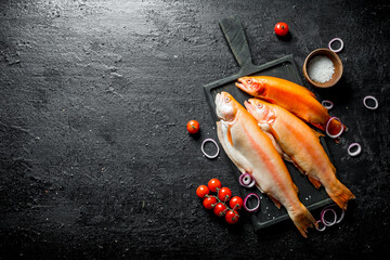 Sticker - Raw fish trout on a cutting Board with onion rings and cherry tomatoes.