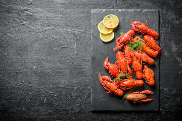 Poster - Boiled crayfish on a black stone Board with slices of lemon.