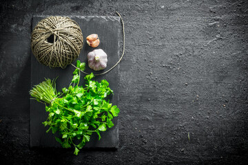 Wall Mural - Fresh parsley on a stone Board with garlic and twine.