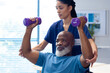 © WavebreakMediaMicro - Diverse female physiotherapist helping senior male patient exercise with dumbbells