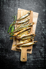 Sticker - Smoked fish on a wooden cutting Board with rosemary.