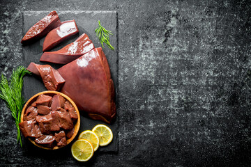 Wall Mural - Pieces of raw liver on a stone Board with pieces of lemon.