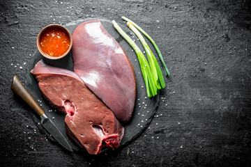 Sticker - Pieces of raw liver on a stone Board with sauce and onions.