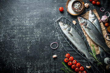 Wall Mural - Raw fish seabass on a grid with tomatoes and spices.