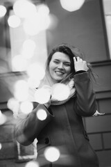 Wall Mural - Close up smiling lady posing with bokeh lights monochrome portrait picture. Closeup front view photography with building on background. High quality photo for ads, travel blog, magazine, article