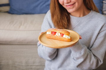 Wall Mural - Closeup image of a woman holding a plate of strawberry Eclair