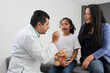 © Arlette - Latina mother cares for and accompanies her curly little daughter at the dark-haired pediatrician specialist doctor's office to prevent abuse and harassment at her medical checkup