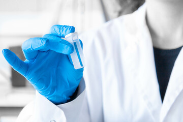 close up scientist hand holding a spectrophotometry cuvette with blue gloves. lab equipment for spec