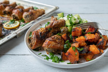 Chicken Drumsticks With Roasted Sweet Potatoes And Cucumber Salad On A Plate