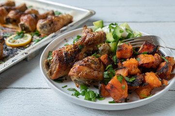 Wall Mural - Chicken drumsticks with roasted sweet potatoes and cucumber salad on a plate